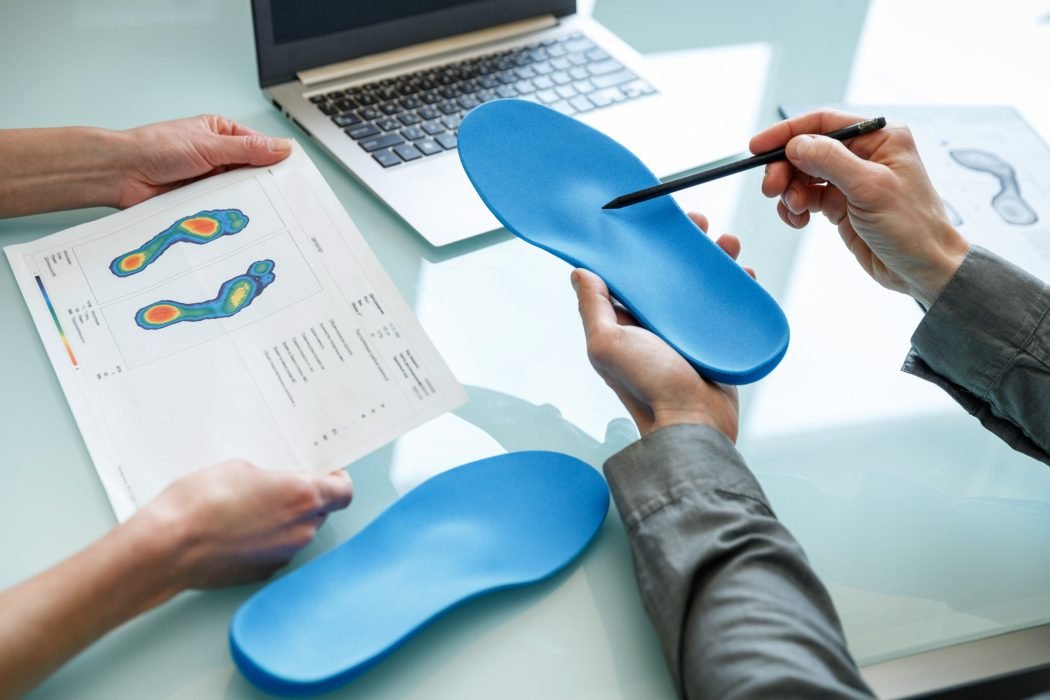 Doctor consulting patient on custom orthotic insoles in a clinic for a personalised custom fit. Feet recreation medicine concept